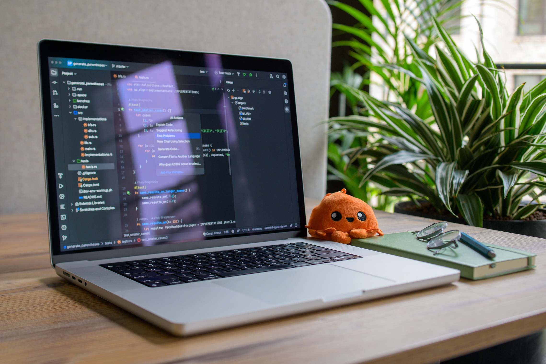 Open laptop on a desk in a workspace with coding interface and plant